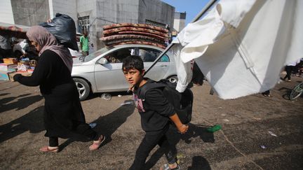 Un jeune garçon palestinien porte un drapeau blanc de fortune alors qu'il arrive avec sa mère près de l'hôpital Al-Shifa dans la ville de Gaza, le 6 novembre 2023. (BASHAR TALEB / AFP)