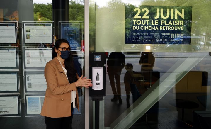 Natacha Bouchaudon, directrice de l'UGC Paris 19, se nettoye les mains avec un distributeur de gel hydroalcoolique disposé dans le cinéma.&nbsp; (THOMAS COEX / AFP)