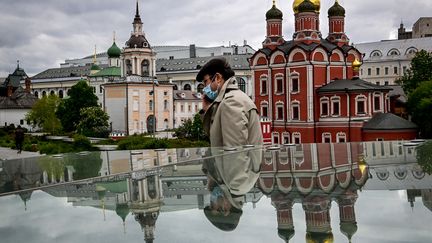 Un homme portant un masque passe devant des cathédrales orthodoxes russes dans le parc Zaryadye à Moscou, le 24 mai 2022. Photo d'illustration. (YURI KADOBNOV / AFP)