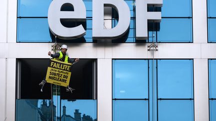 Un militant Greenpeace durant une action au siège d'EDF, le 14 février 2017. (ERIC PIERMONT / AFP)