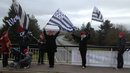 Des "bonnets rouges" brandissent des drapeaux, sur un pont enjambant une voie express, en Bretagne. (STEPHANE IZAD - FRANCE 3 BRETAGNE)