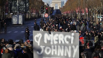 Un panneau "merci Johnny" brandi par l'un des nombreux fans qui attendent le passage du cortège funéraire de leur idole, samedi 9 décembre 2017 sur les Champs-Élysées
 (Patrick Kovarik / AFP)