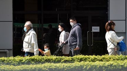 Des personnes portent un masque dans les rues de Hong Kong, une des villes encore très touchées par la pandémie de Covid-19, le 24 février 2022. (LO PING FAI / XINHUA / AFP)