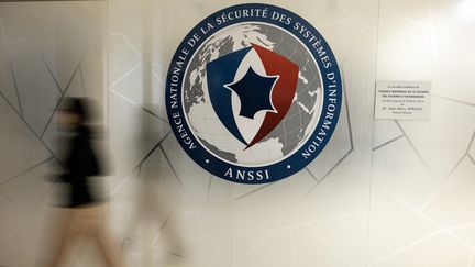 Un agent passe devant le logo du centre opérationnel de l'agence nationale de sécurité des systèmes informatiques (Anssi) à Paris, le 24 novembre 2022. (THOMAS SAMSON / AFP)