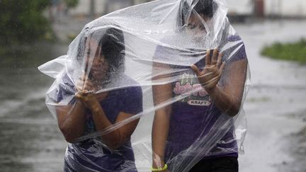 Des jeunes femmes se prot&egrave;gent du vent et de la pluie caus&eacute;s par le passage du typhon Hagupit &agrave; Legazpi (Philippines), le 7 d&eacute;cembre 2014. (AARON FAVILA / AP / SIPA)