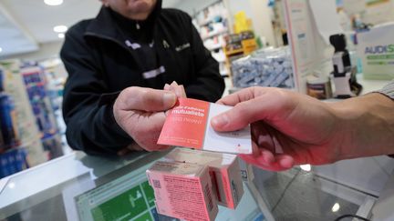 Un client d'une pharmacie présente sa carte de mutuelle pour l'achat de médicaments. Photo d'illustration. (FRANCOIS DESTOC / MAXPPP)