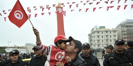 Un enfant, brandissant le drapeau tunisien, embrasse son père à Tunis lors des festivités marquant le second anniversaire de la révolution. (AFP - FETHI BELAID )