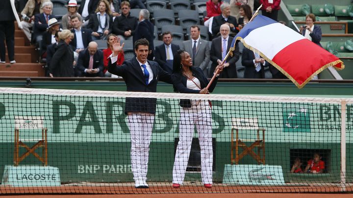 Le cano&eacute;iste Tony Estanguet (&agrave; gauche) transmet le drapeau de la France &agrave; l'&eacute;p&eacute;iste Laura Flessel, le 10 juin 2012 &agrave; Roland Garros (Paris). (KENZO TRIBOUILLARD / AFP)