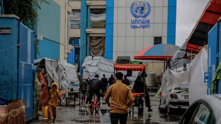 Des Palestiniens devant une école de l'UNWRA convertie en lieu d'accueil pour les réfugiés, le 27 novembre 2023. (OMAR EL-QATTAA / AFP)