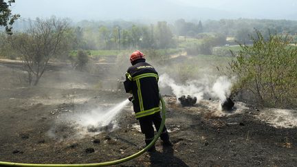 Un pompier du Var&nbsp;éteint les restes de végétation fumante dans le massif des Maures, le 17 août 2021. (NICOLAS TUCAT / AFP)