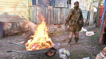 Un séparatiste prorusse met le feu à une brouette remplie de drogue, le 30 avril 2022 à Louhansk (Ukraine). (VIKTOR ANTONYUK / SPUTNIK  /AFP)