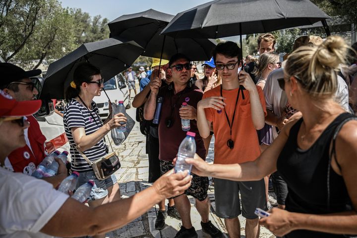 La Croix Rouge distribue des bouteilles d'eau aux touristes à l'Acropole d'Athènes, le 12 juillet 2023 (ANGELOS TZORTZINIS / AFP)