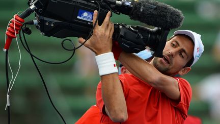 Le Serbe Novak Djokovic se filme avec une cam&eacute;ra de t&eacute;l&eacute;vision avant une match d'exhibition &agrave; Melbourne (Australie), le 9 janvier 2014. (WILLIAM WEST / AFP)