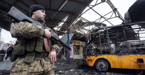 Un membre des forces armées sécessionnistes pro-russes à Donetsk (est de l'Ukraine) monte la garde près d'un véhicule incendié dans une station de bus après un bombardement le 11 février 2015. (Reuters - Maxim Shemetov)