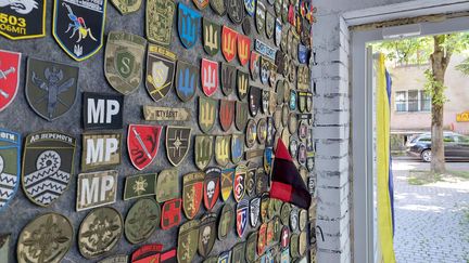 Une série d'écussons militaires, sur le mur de l'atelier d'Oksana qui attend son mari. (Julie Pietri / Radio France)