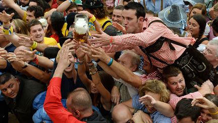 Des festivaliers tentent d'attraper la premi&egrave;re bi&egrave;re servie lors de l'ouverture de l'Oktoberfest, &agrave; Munich (Bavi&egrave;re, Allemagne), le 21 septembre 2013. (CHRISTOF STACHE / AFP)