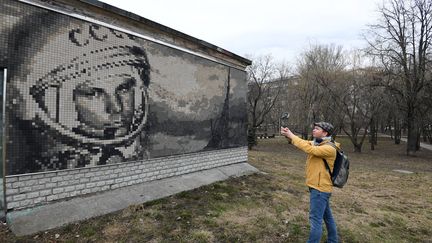 Un touriste prend une photo d'une mosaïque représentant&nbsp;Youri Gagarine,&nbsp;premier homme placé en orbite autour de la Terre. (NATALIA KOLESNIKOVA / AFP)