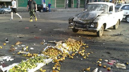 Cette photo de l'agence officielle Sana montre un membre des forces de sécurité syriennes à côté d'un camion endommagé par un attentat-suicide dans la ville de Soueïda, le 25 juillet 2018. (SANA / AFP)