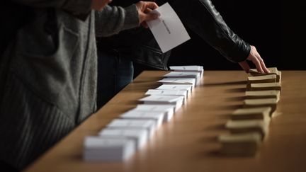 Des élécteurs prennent leurs bulletins de vote dans un bureau de Strasbourg (Bas-Rhin), pour le premier tour de l'élection présidentielle, le 23 avril 2017. (FREDERICK FLORIN / AFP)