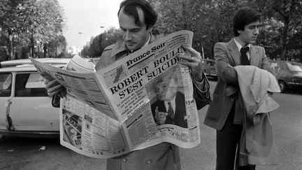 Un homme lit le journal "France Soir"&nbsp;qui évoque la mort de Roubert Boulin, à Paris, le 30 octobre 1979. (GEORGES BENDRIHEM / ARCHIVES / AFP)