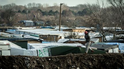 Un migrant mmarche sur un talus, le long de la "jungle", à Calais, le 19 février 2016. (PHILIPPE HUGUEN / AFP)