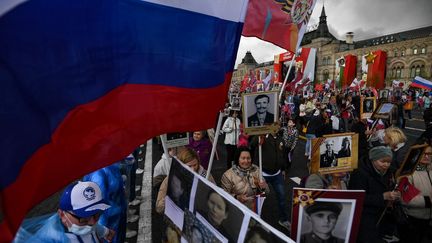 Des personnes portent des portraits de leurs proches, engagés durant la Seconde Guerre mondiale, sur la Place Rouge, dans le centre de Moscou (Russie), le 9 mai 2022. (NATALIA KOLESNIKOVA / AFP)