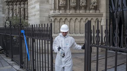 Un ouvrier du bâtiment passe une porte à la cathédrale Notre-Dame de Paris lors des travaux préliminaires du 24 juillet 2019 à Paris, trois mois après les dégâts causés par un énorme incendie le 15 avril dernier. (RAFAEL YAGHOBZADEH / POOL)