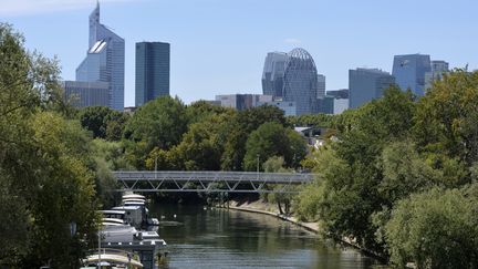 Le centre d'affaires de la Défense émergeant derrière un rideau d'arbres au pont de Levallois à Levallois-Perret (2015). (MIGUEL MEDINA / AFP)