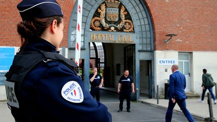 Un policier se tient devant le CHU de Reims après l'attaque au couteau (FRANCOIS NASCIMBENI / AFP)