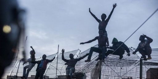 Migrants sur une des clôtures entourant l'enclave espagnole de Melilla en territoire marocain (mars 2014). (JOSE COLON / AFP)