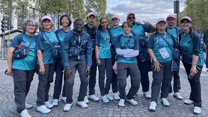 Jade, au centre, et plusieurs bénévoles de la ville de Paris ayant œuvré pendant les Jeux ont défilé sur les Champs-Élysées, samedi 14 septembre. (Clément Mariotti Pons / franceinfo : sport)