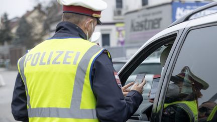 Un policier autrichien contrôle les certificats de vaccination lors d'un contrôle routier alors que débute un confinement des personnes non vaccinées, à Graz, lundi 15 novembre. (ERWIN SCHERIAU / APA)