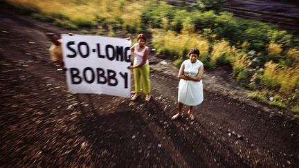 Le 8 juin 1968, trois jours après son assassinat, le corps de Robert F. Kennedy était transporté en train de New York à Washington. L'exposition suit ce dernier voyage, avec les photos prises depuis le train par Paul Fusco des Américains endeuillés le long du parcours, et avec des photos amateurs réalisés à l'extérieur et réunies par Rein Jelle Terpstra. Ici, Paul Fusco/Magnum Photos, sans titre, série RFK Funeral Train, 1968. Avec l’aimable autorisation de la Danziger Gallery
 (Rencontres d&#039;Arles)