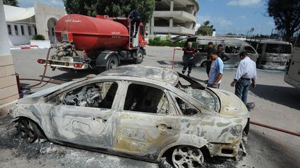 Des Tunisiens d&eacute;couvrent des voitures et bus incendi&eacute;s &agrave; l'&eacute;cole am&eacute;ricaine de Tunis, le 15 septembre 2012. (FETHI BELAID / AFP)