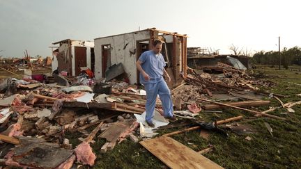 Un habitant de Moore, une ville de la banlieue d'Oklahoma City (Etats-Unis), marche&nbsp;au milieu des d&eacute;combres de sa maison, d&eacute;truite par&nbsp;une tornade, le 20 mai 2013. (BRETT DEERING / GETTY IMAGES NORTH AMERICA / AFP)