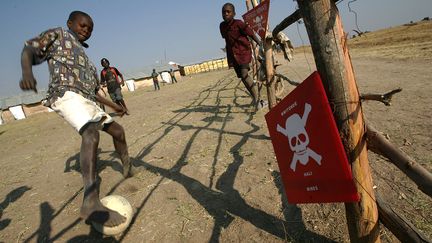 Des enfants angolais jouent près d'un champ de mines dans le camp de réfugiés de Huambo (est du pays), le 7 juillet 2005.&nbsp; (ALEXANDER JOE / AFP)