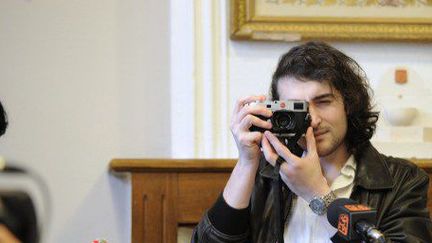 Edouard Elias, photographe qui fut détenu en Syrie, prend en photo les journalistes venus l'interviewer après son retour (avril 2014). (SYLVAIN THOMAS / AFP)