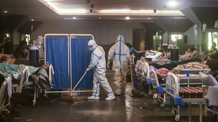 Une personne nettoie le sol d'une salle des fêtes convertie en hôpital de campagne, le 1er mai 2021, à New Delhi (Inde). (PRAKASH SINGH / AFP)