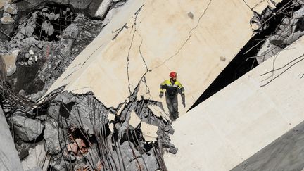 Un sauveteur italien explore les décombres du pont Morandi, à Gênes, le 14 août 2018. (VALERY HACHE / AFP)