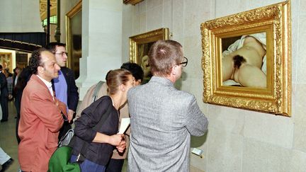 Des visiteurs devant le tableau de Gustave Courbet "L'Origine du monde" exposé au musée d'Orsay à Paris. (PASCAL GUYOT / AFP)