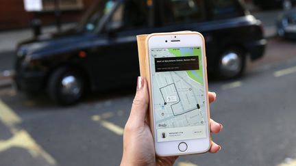 Une utilisatrice commande un Uber à Londres (Royaume-Uni), le 22 septembre 2017. (DANIEL LEAL-OLIVAS / AFP)