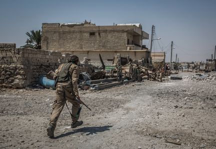 Un soldat des forces démocratique syrienne court dans une rue du quartier d'Al-Sinaa, à Raqqa (Syrie) pour tenter d'échapper à d'éventuels tirs de snipers.&nbsp; (MORUKC UMNABER / DPA / AFP)