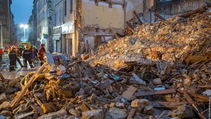 Des pompiers et un&nbsp;chien renifleur recherchent d'éventuelles victimes dans les décombres des immeubles effondrés, rue d'Aubagne à Marseille, le 6 novembre 2018. (LOIC AEDO / BMPM / AFP)