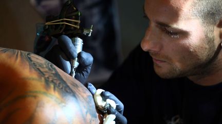 Un tatoueur utilise de l'encre de couleur lors de la neuvi&egrave;me convention internationale du tatouage, &agrave; Londres, le 27 septembre 2013. (REX / PAUL BROWN / SIPA )