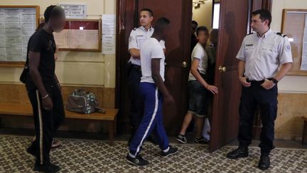 Trois hommes suspect&eacute;s d'avoir pris part aux violences &agrave; Trappes entrent dans la salle d'audience du tribunal de Versailles (Yvelines), le 22 juillet 2013. (FRANCOIS GUILLOT / AFP)