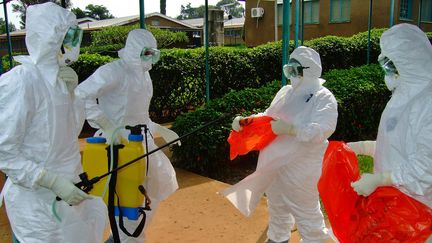 Des membres de l'Organisation mondiale de la sant&eacute; portent des tenues de protection avant de p&eacute;n&eacute;trer dans l'h&ocirc;pital ougandais de Kagadi, le 28 juillet 2012. (ISAAC KASAMANI / AFP)