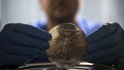 Au Brésil, un ouvrier tient dans ses mains une des médailles qui seront remises aux athlètes. (CHRISTOPHE SIMON / AFP)