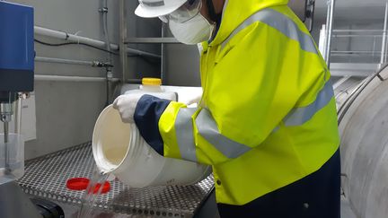 Un employé de la&nbsp;station d'épuration de Colombes, dans les Hauts-de-Seine, manipule de l'eau usée après filtration. (SOLENNE LE HEN / RADIO FRANCE)