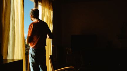 Un homme regarde le paysage par la fenêtre de son logement lors du second confinement à Cassagne (Haute-Garonne), le 25 novembre 2020. (LILIAN CAZABET / HANS LUCAS)