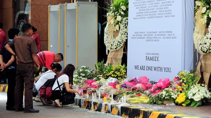 Des employés du casino de Manille (Philippines) déposent des fleurs et des bougies devant l'entrée de l'établissement, le 4 juin 2017, après une attaque qui a fait 37 morts. (ROMEO RANOCO / REUTERS)